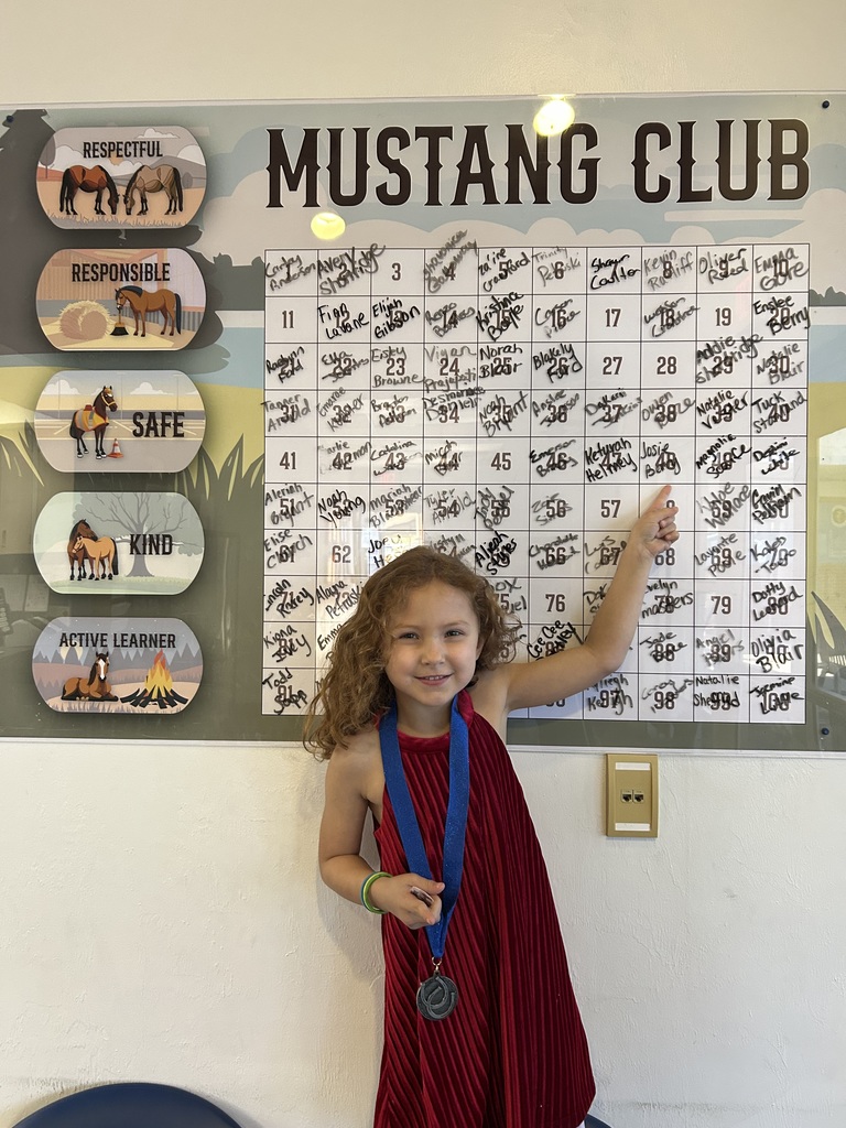 Picture of female student pointing at the Mustang Club board.