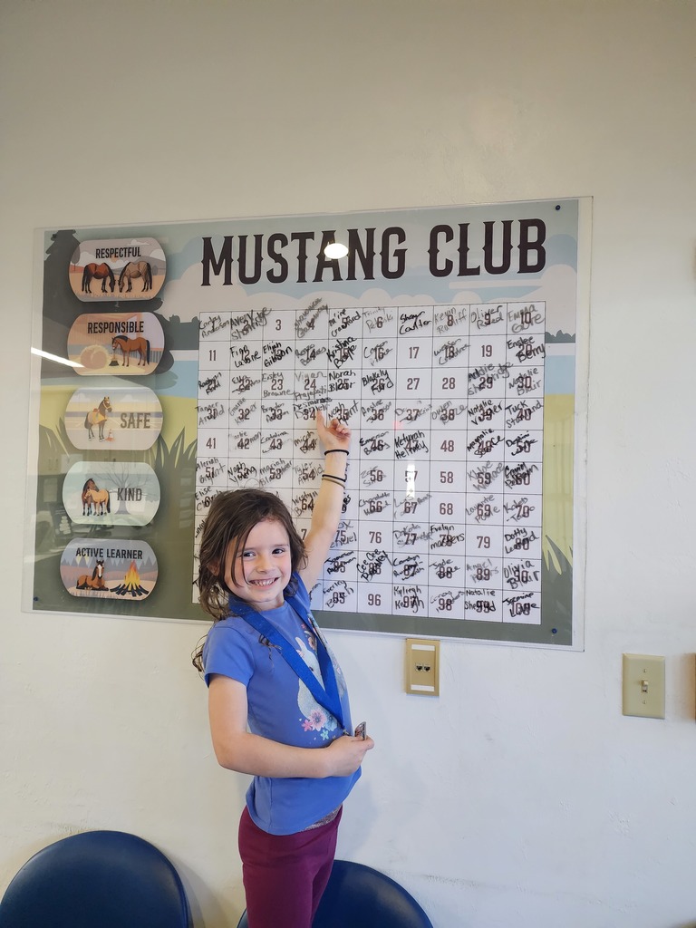 Picture of female student pointing at the Mustang Club board.