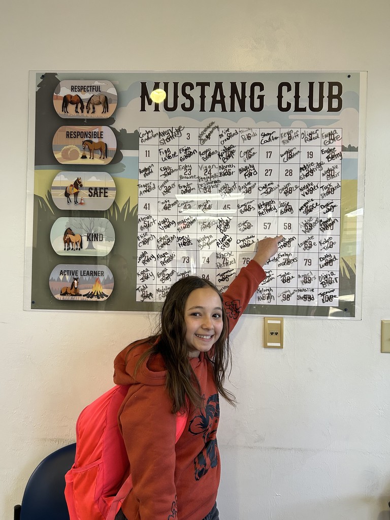 Picture of female student pointing at the Mustang Club board.
