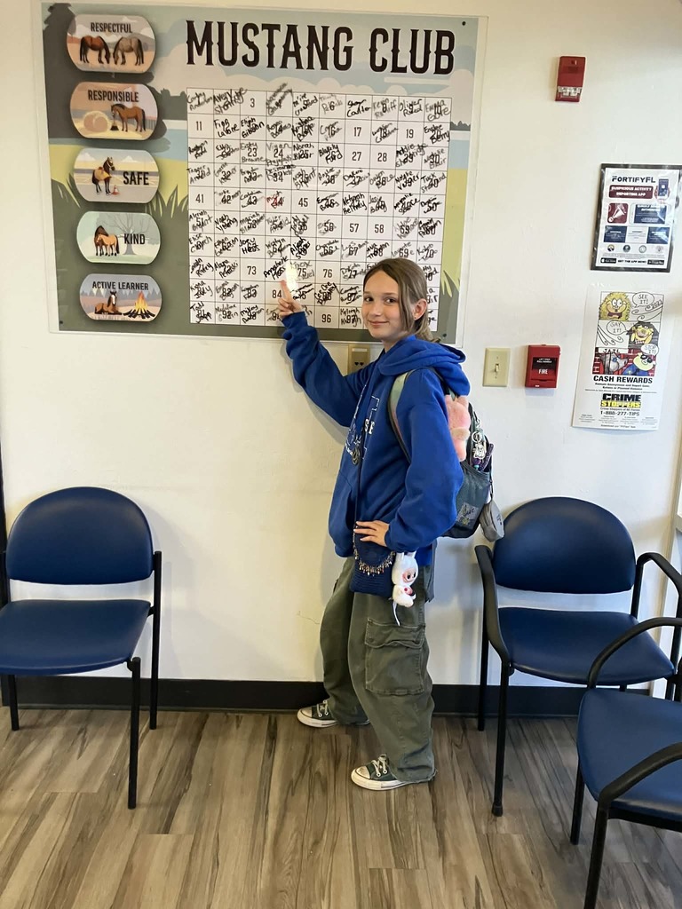 Picture of female student pointing at the Mustang Club board.