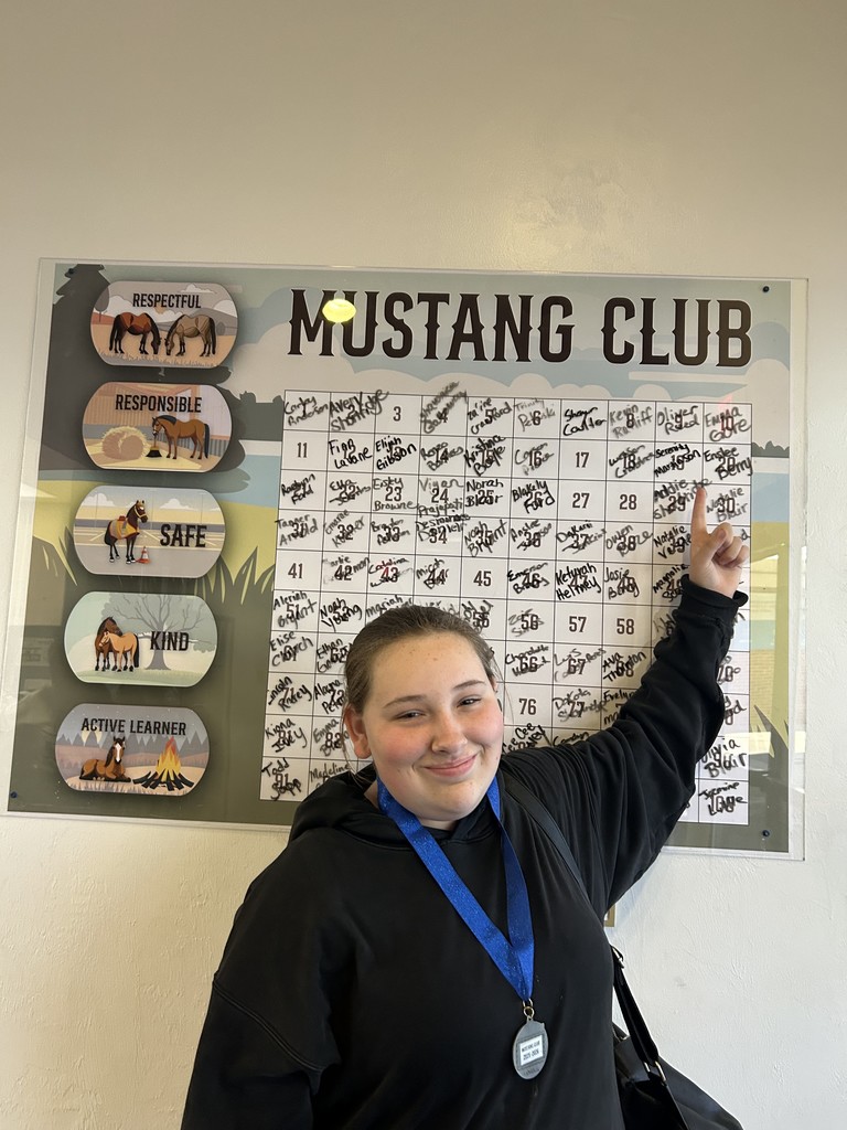 Picture of female student pointing at the Mustang Club board.