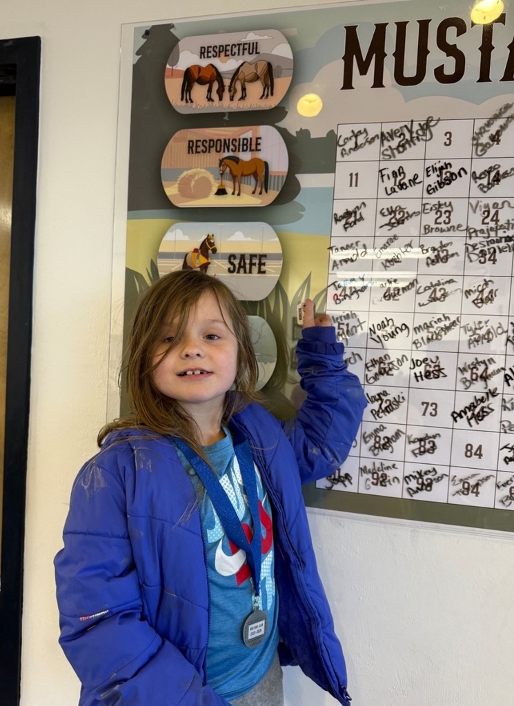 Picture of female student pointing at the Mustang Club board.