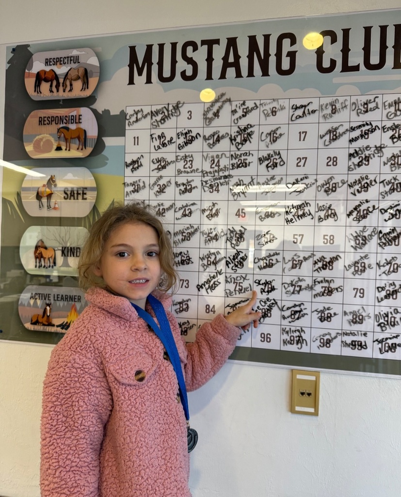Picture of female student pointing at the Mustang Club board.