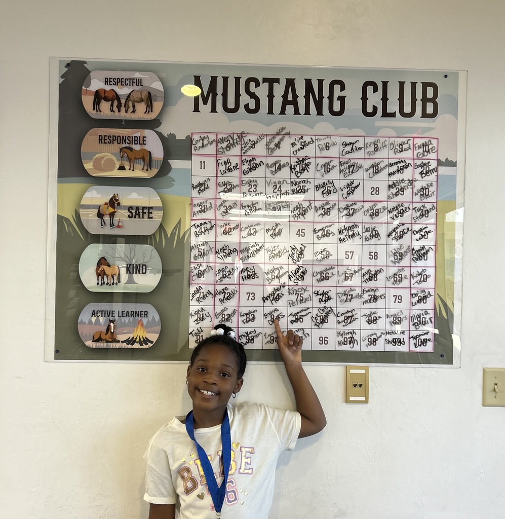 Picture of female student pointing at the Mustang Club board.