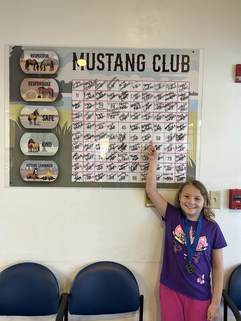 Picture of female student pointing at the Mustang Club board.