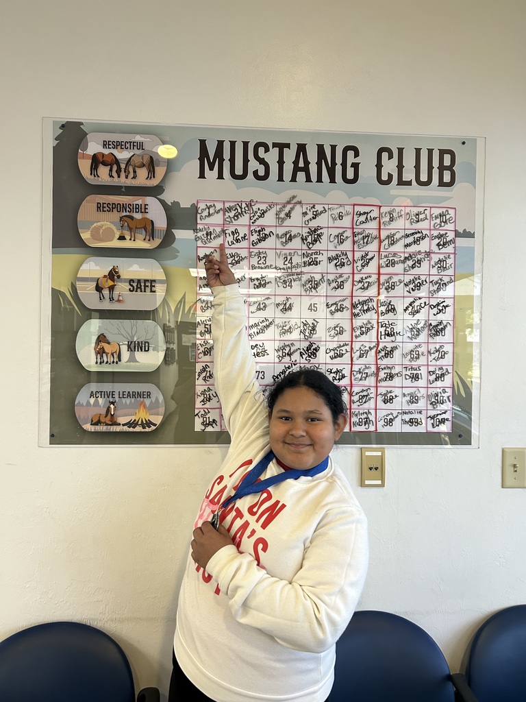 Picture of female student pointing at the Mustang Club board.