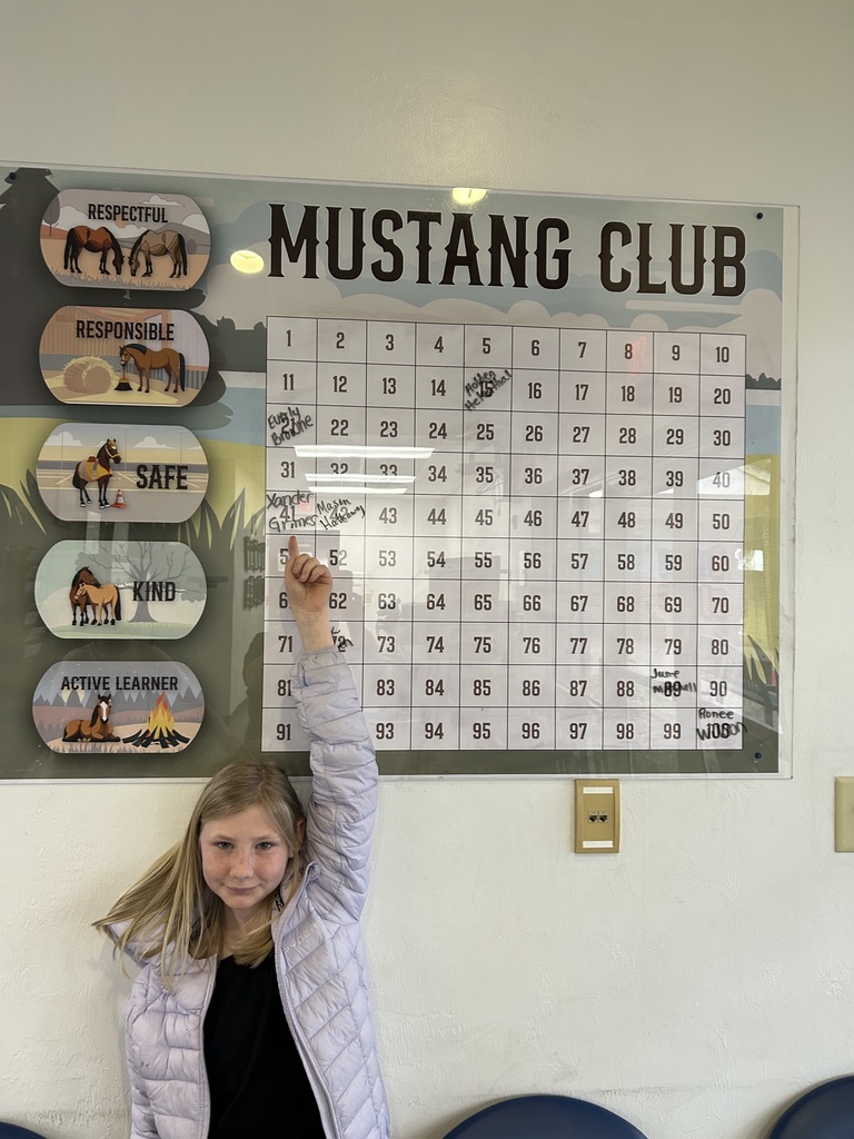 Picture of female student pointing at Mustang Club board 