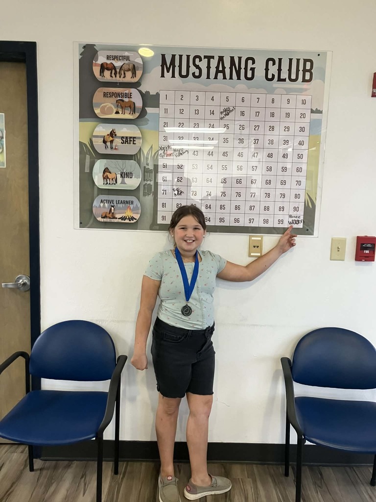Picture of female student pointing at Mustang Club board 