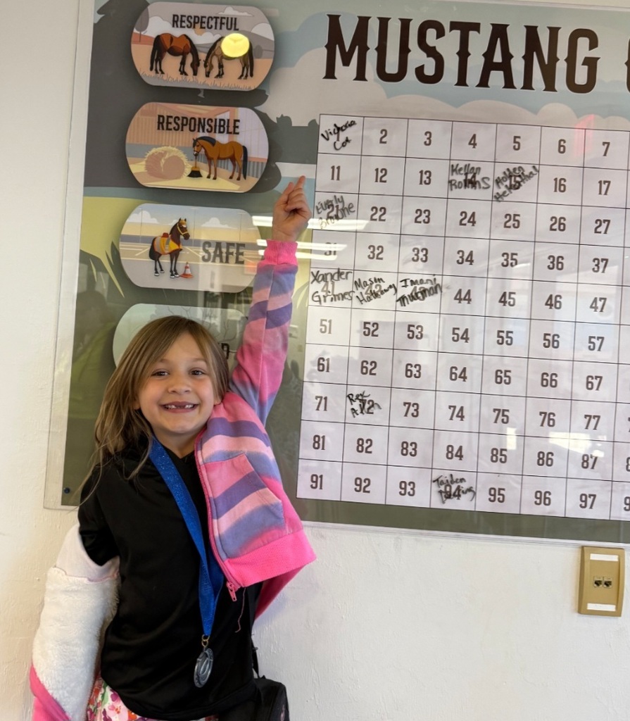 Picture of female student pointing at Mustang Club board