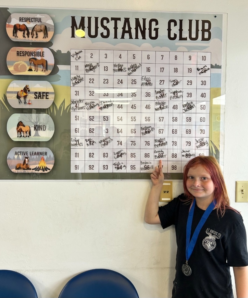 Picture of female student pointing at Mustang Club board 