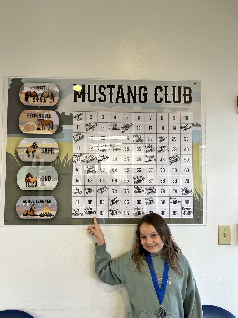 Picture of female student pointing at the Mustang Club board.