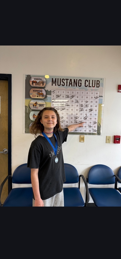 Picture of female student pointing at Mustang Club board 