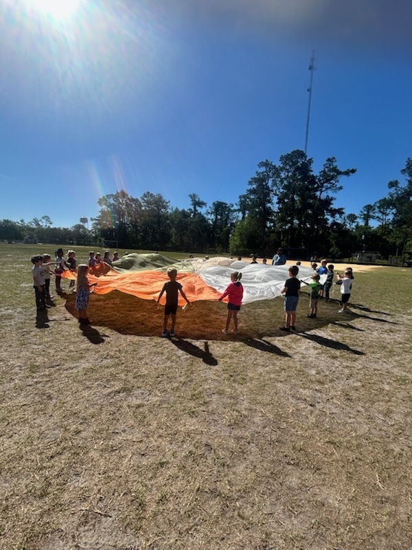 kindergarten students having fun with a parachute