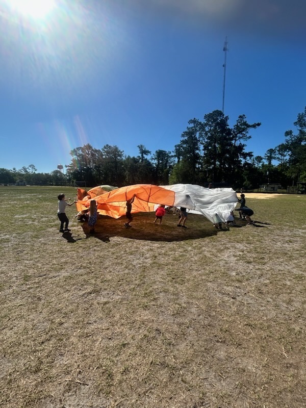 kindergarten students having fun with a parachute
