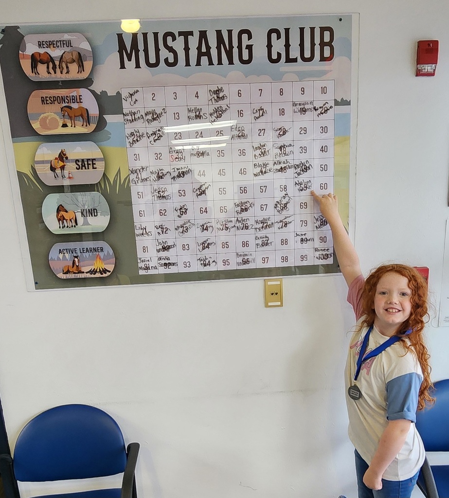 Picture of female student pointing at the Mustang Club board.