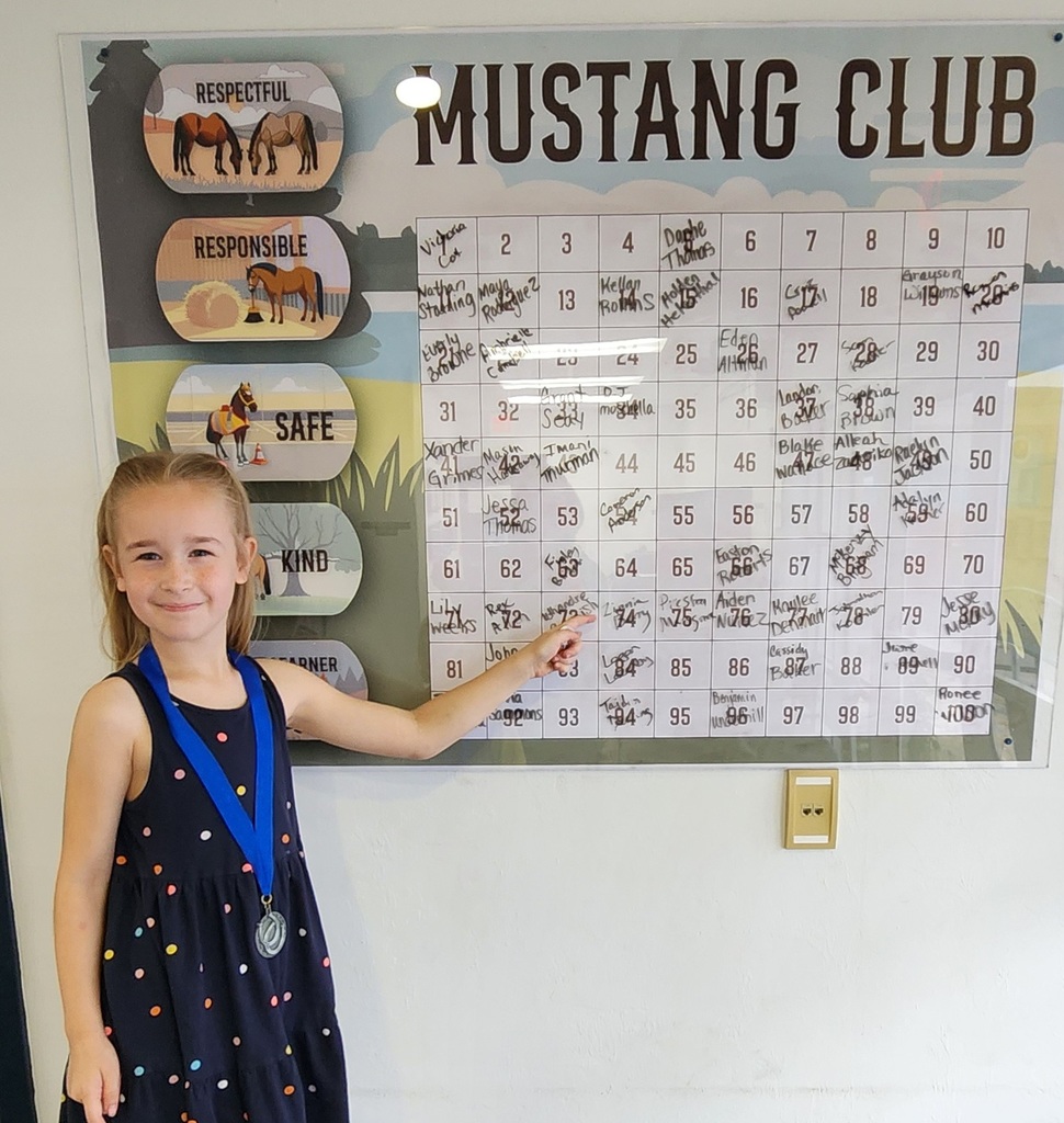 Picture of female student pointing at the Mustang Club board.