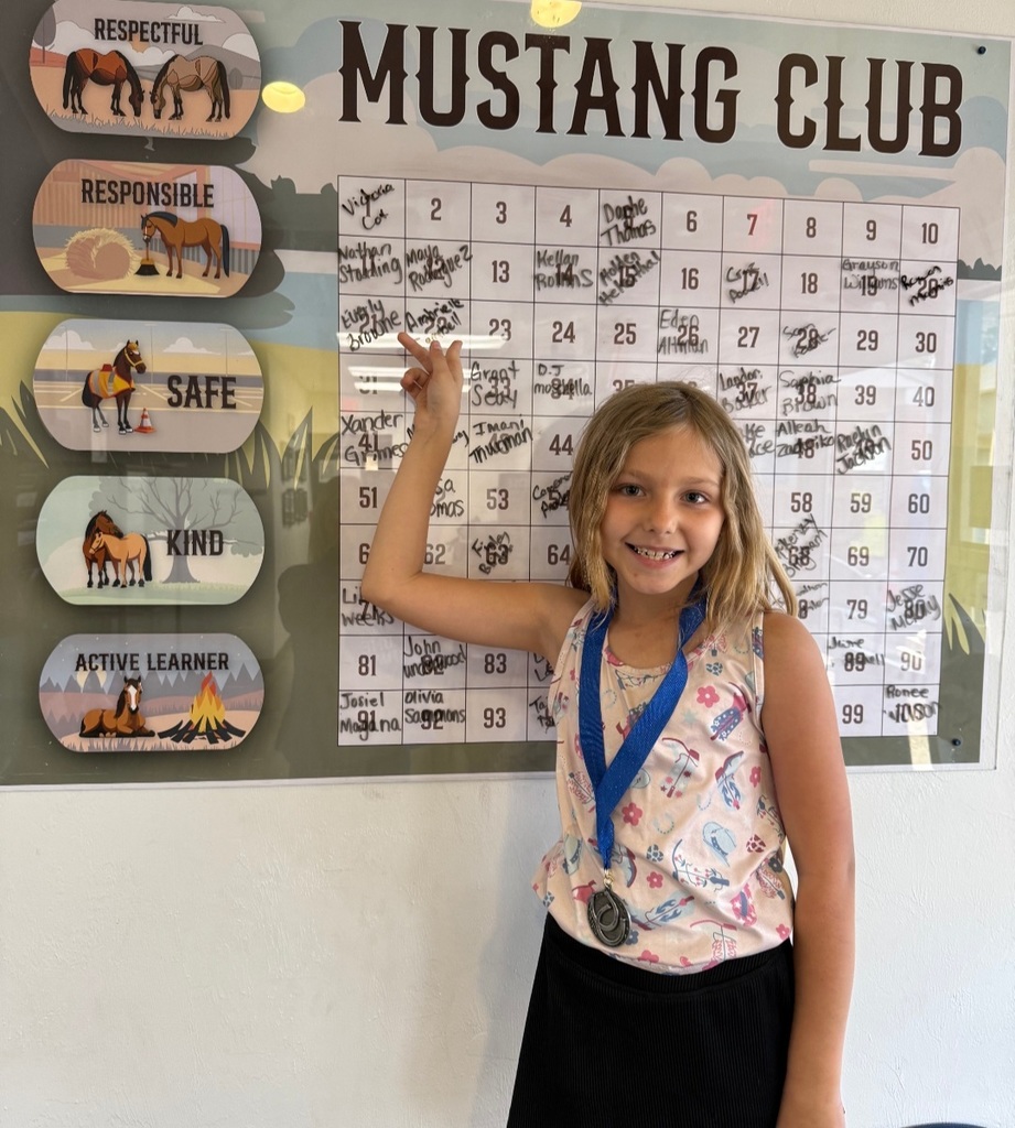 Picture of female student pointing at the Mustang Club board.