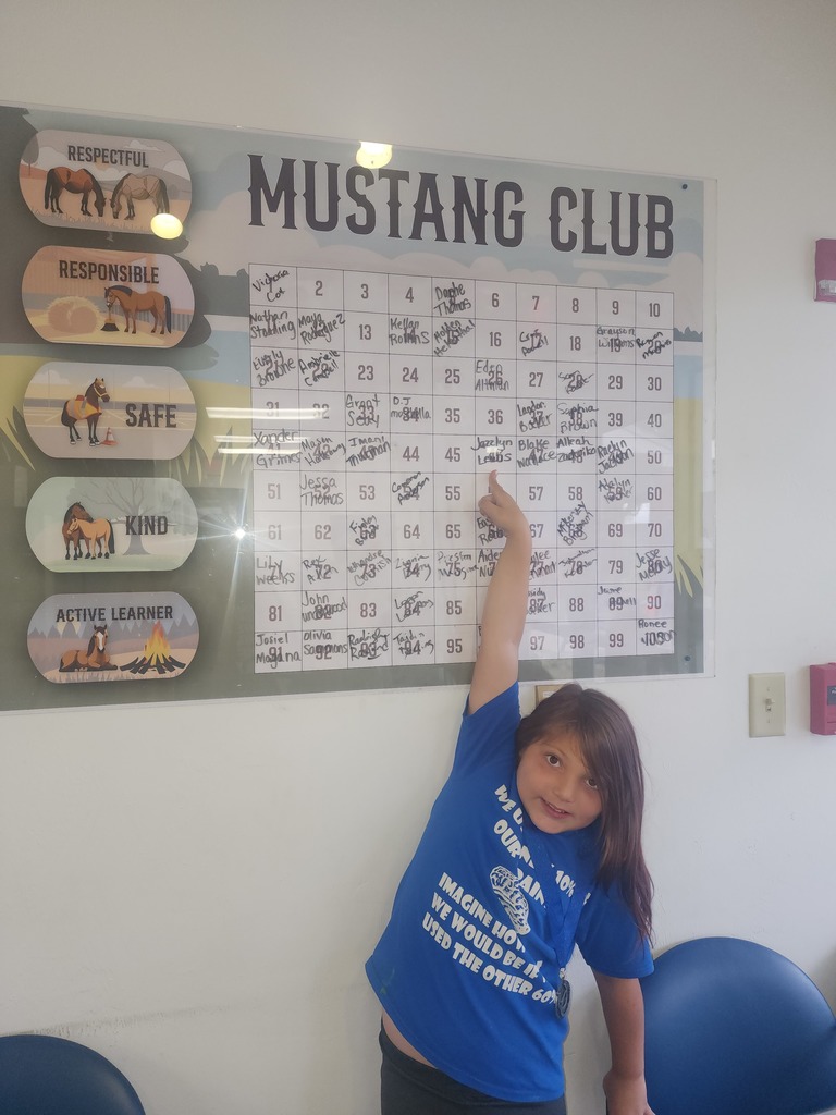 Picture of female student pointing at the Mustang Club board.