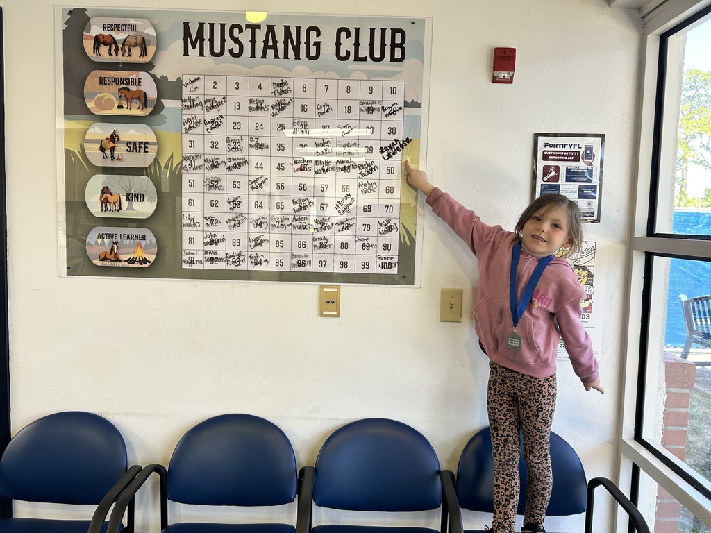Picture of female student pointing at the Mustang Club board.