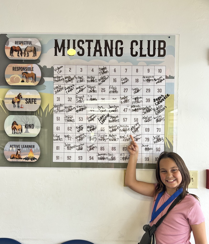 Picture of female student pointing at the Mustang Club board.