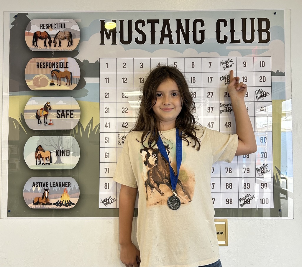 picture of female student in front of congratulations Mustangs sign holding her Mustang Club medal