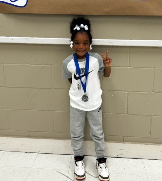picture of female student in front of congratulations Mustangs sign holding her Mustang Club medal
