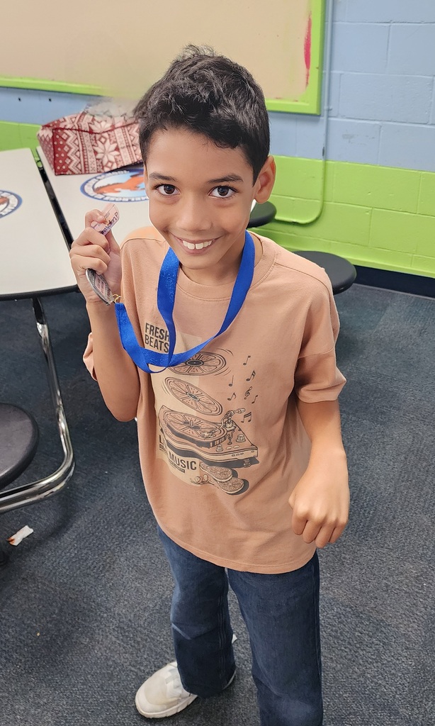 picture of male student in front of congratulations Mustangs sign holding his Mustang Club medal