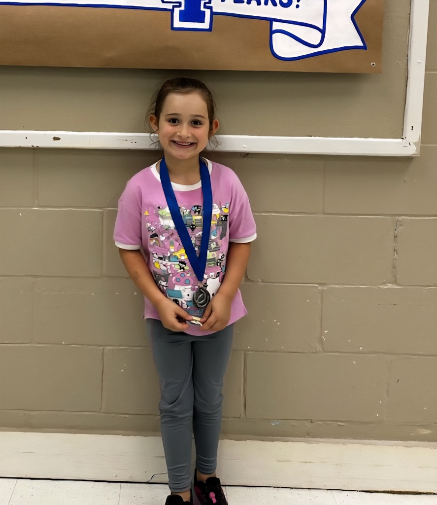 picture of female student in front of congratulations Mustangs sign holding her Mustang Club medal