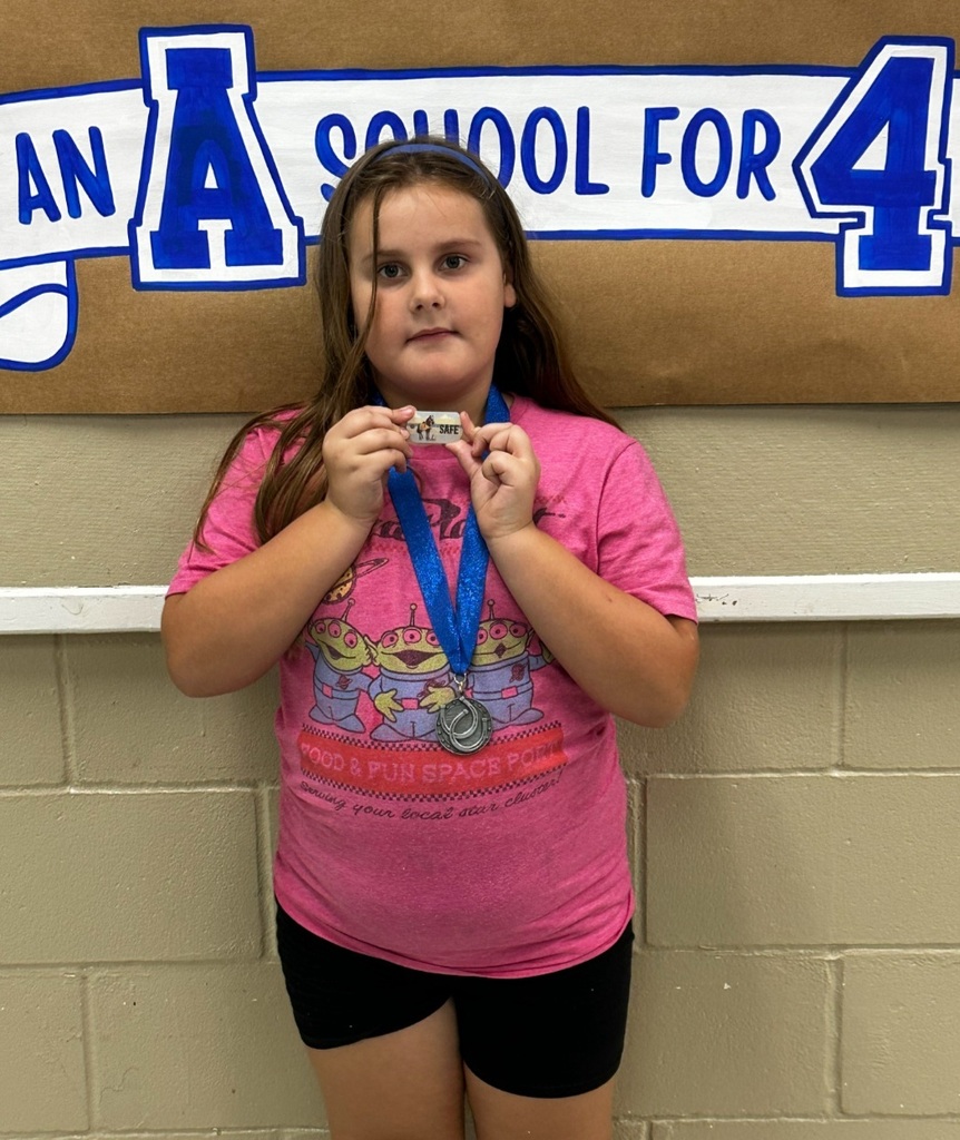 picture of female student holding brag tag with Mustang Club medal