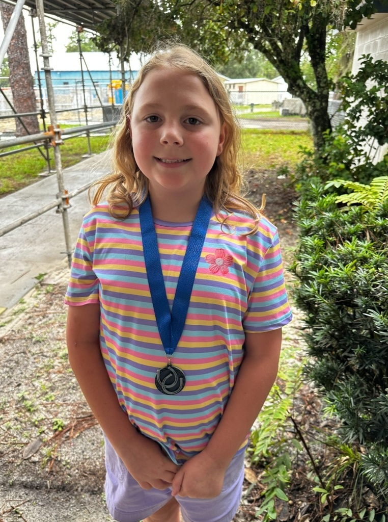 picture of female student wearing a Mustang Club medal standing outside