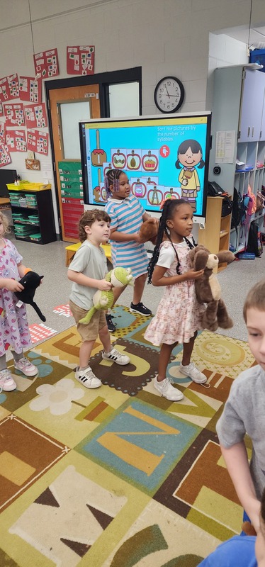 picture of kindergarten students walking in a parade with their stuffed animals.