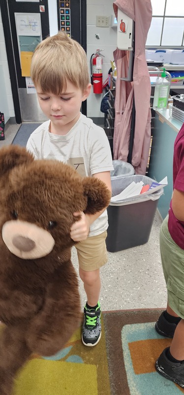 picture of kindergarten students walking in a parade with their stuffed animals.