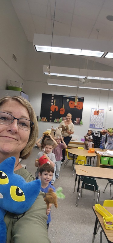 picture of kindergarten students walking in a parade with their stuffed animals.