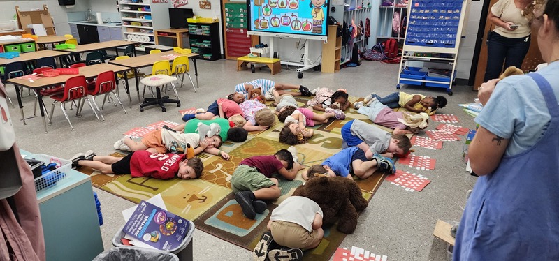 picture of the kindergarten students and stuffed animals all going to sleep after the parade