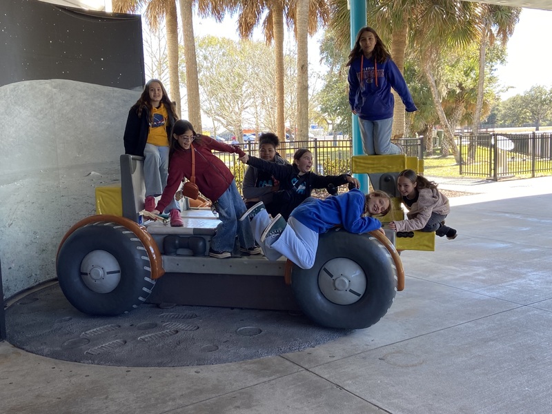 picture of female students on land rover type sculpture