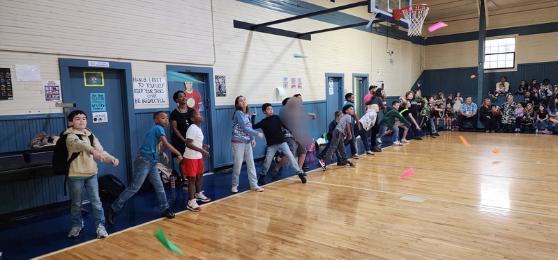 pictures of boys and girls throwing airplanes in the gym