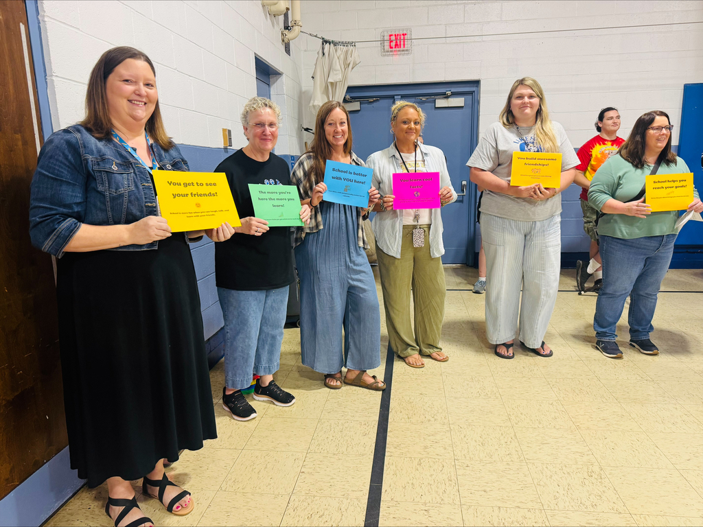 Staff members in a line waiting to read their top 20 reason school is important. 