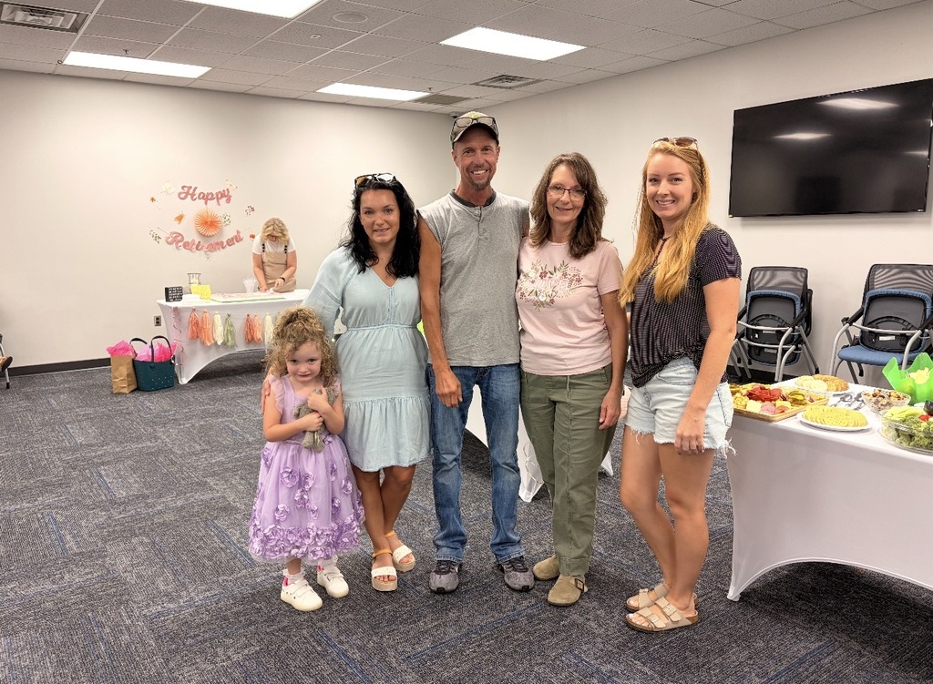 Lisa King and family in front of refreshment table at retirement celebration. 