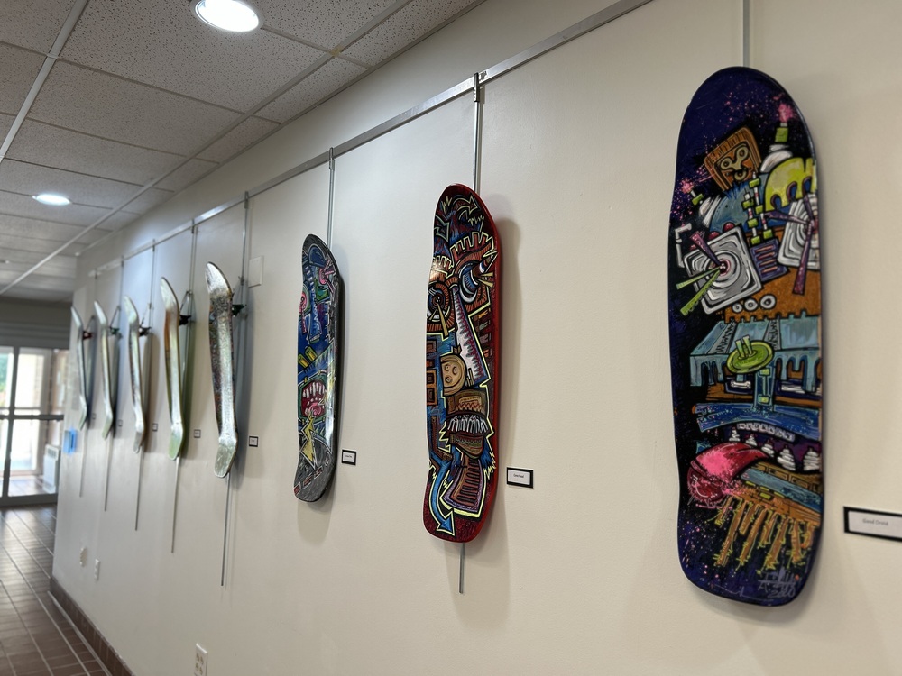 A photo of skateboard decks  that are painted with images of radios, guitars and other lifestyle objects