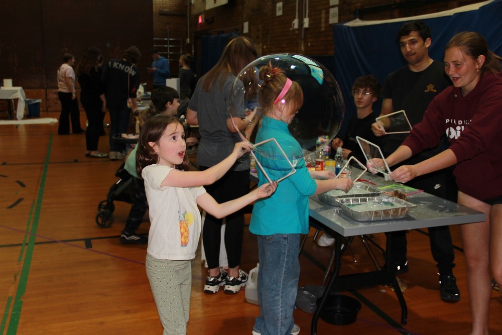 Child makes a huge bubble at the bubble station