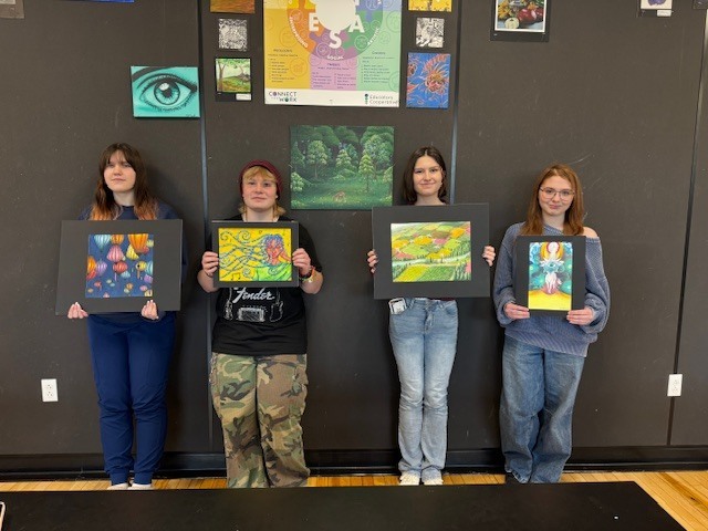 All four students holding up their art work