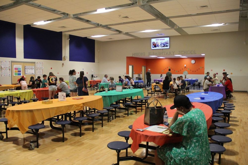 The Neidig Cafeteria decorated in colorful table clothes and families doing literacy games.