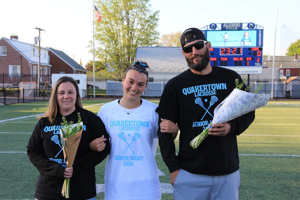 Kayla smiling with her parents on the field.