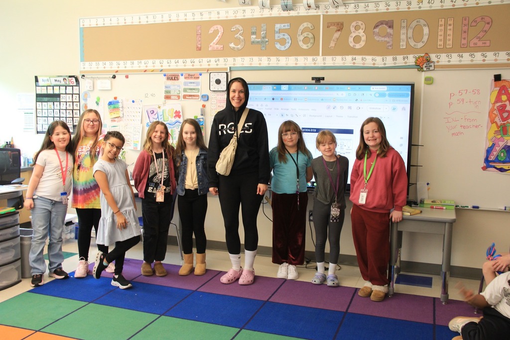 Students smile with their teacher - all wearing comfy clothes to be warm in the classroom.