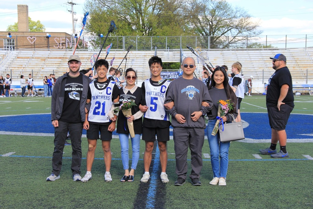 Brandon and Collin Nguyen smile for a photo with their family on the field.