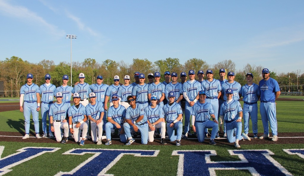 Varsity Baseball team smiles on the field with their coaches