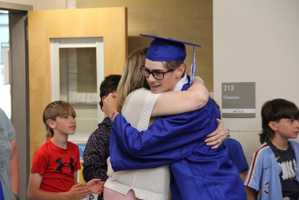 Seniors in their caps and gowns hug former teachers