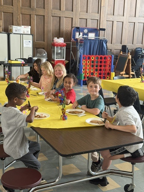 Students seated at decorated tables enjoying their pancakes