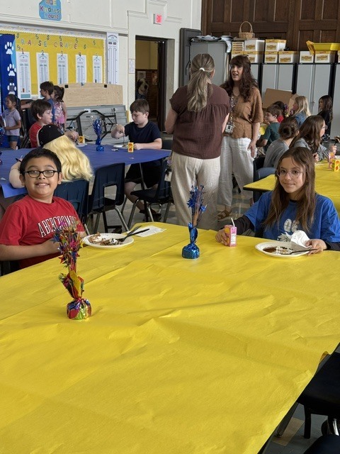 Students seated at decorated tables enjoying their pancakes