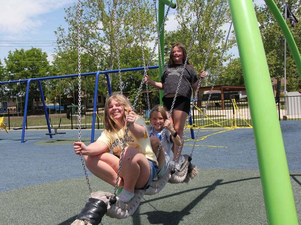 Three 5th grade girls smile for a photo on playgound equipment